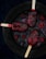 Four dark red popsicles are arranged on a round, black plate, surrounded by scattered blackberries and blueberries. The popsicles have a rich, berry-infused appearance, with visible fruit pieces embedded inside. The plate is set against a deep, dark background, enhancing the vibrant colors of the berries and popsicles.