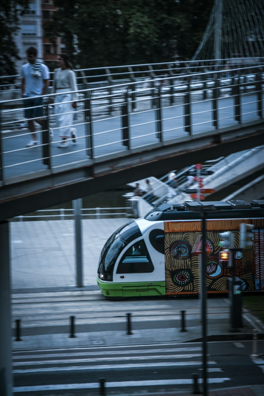 um trem verde e branco viajando sob uma ponte