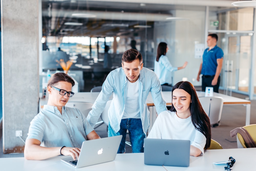 eine gruppe von menschen, die um einen tisch mit laptops sitzen