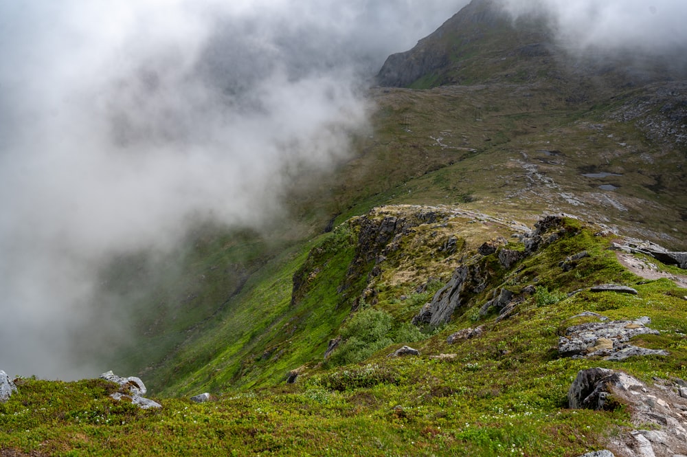 a mountain covered in clouds and green grass
