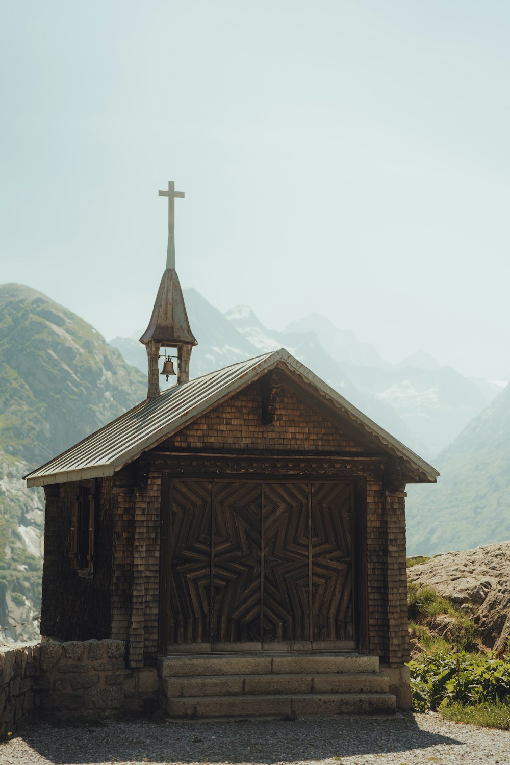 a small wooden building with a cross on top of it