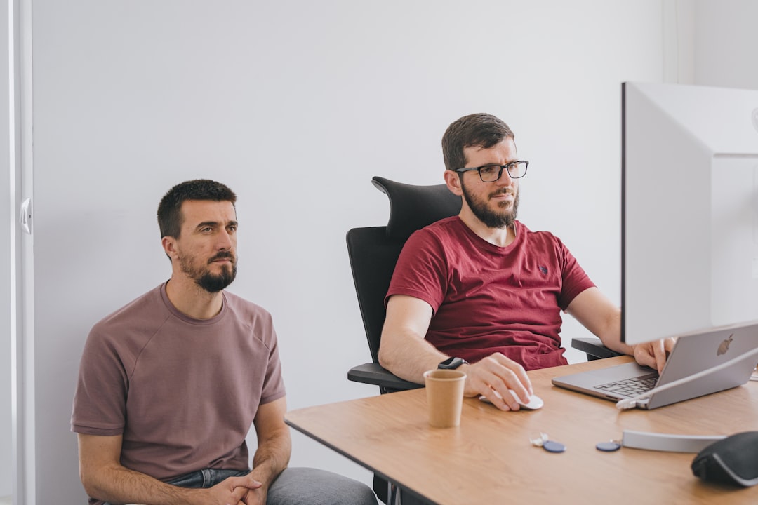 two men sitting at a table with a laptop, Two young entrepreneurs of a tech company discussing about projects.