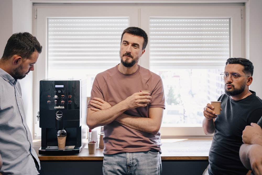 a group of men standing around a coffee machine