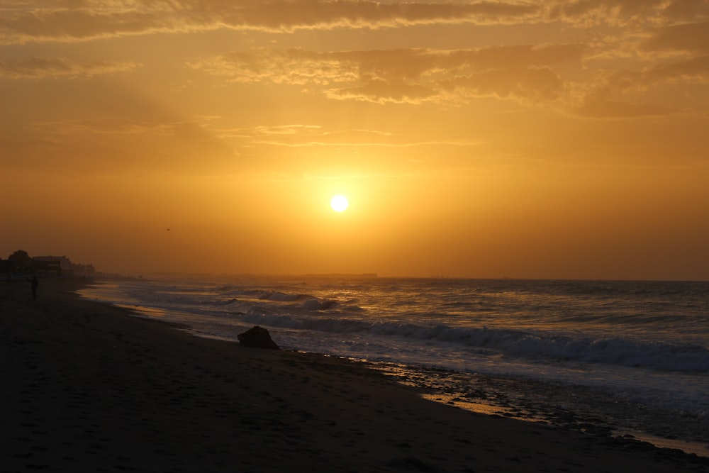 the sun is setting over the ocean on the beach