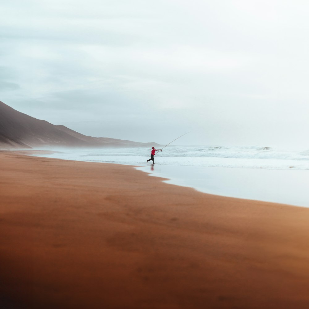 eine person am strand mit einem drachen