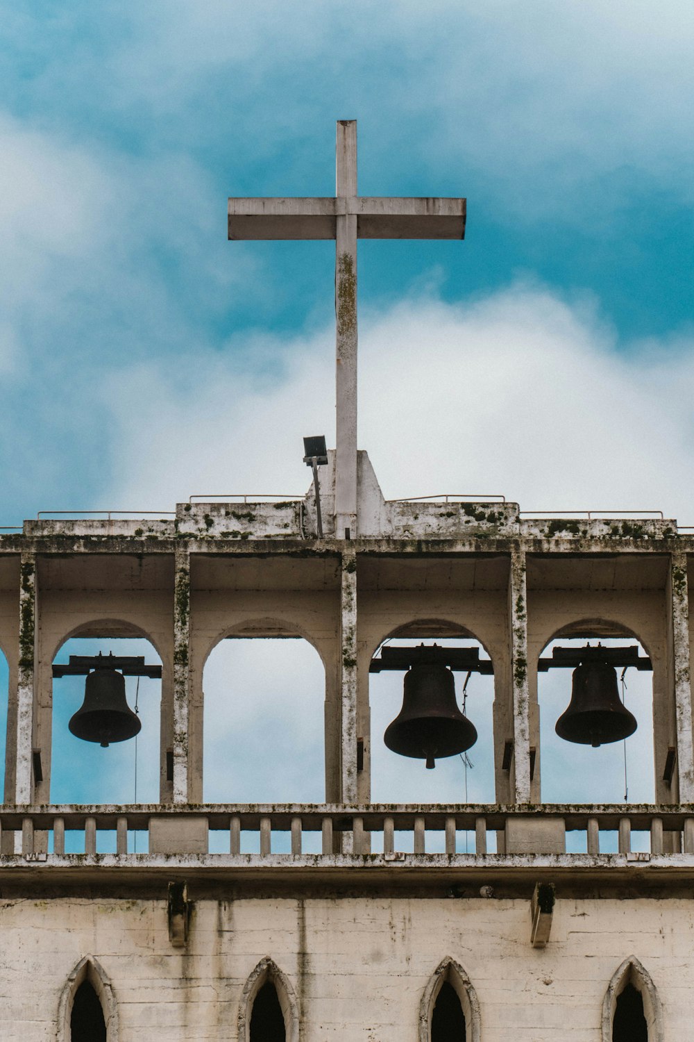une croix au sommet d’un bâtiment avec des cloches