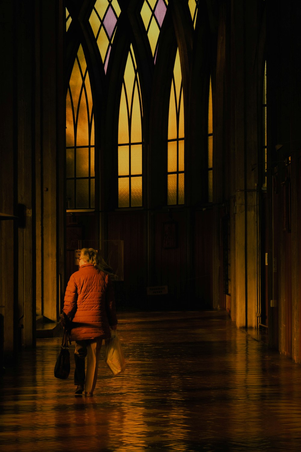 a woman in a red jacket walking down a hall