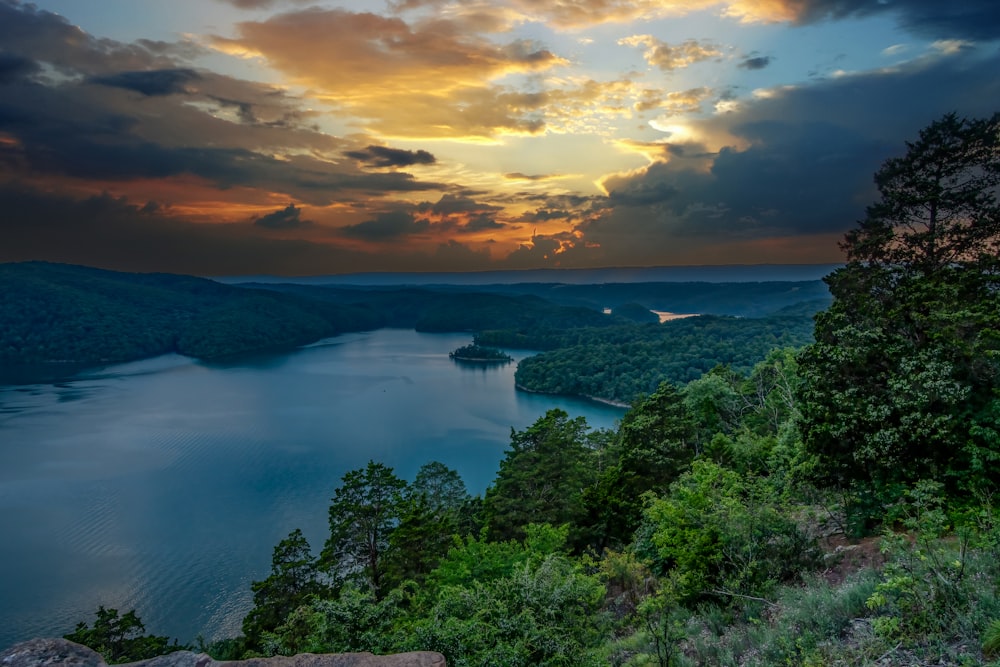 the sun is setting over a lake in the mountains