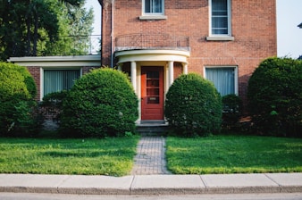 a brick house with a red door and green grass