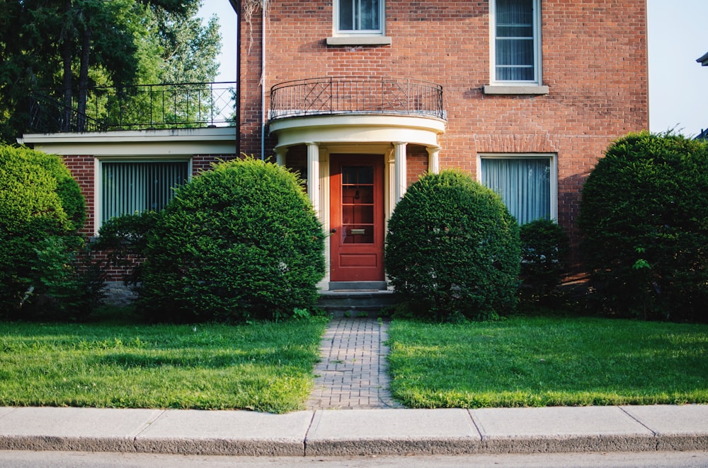 a brick house with a red door and green grass