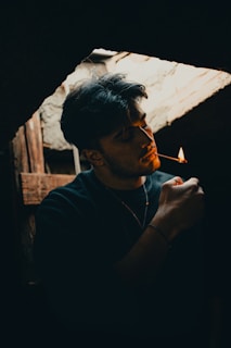 a man smoking a cigarette in a dark room