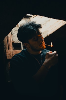 a man smoking a cigarette in a dark room