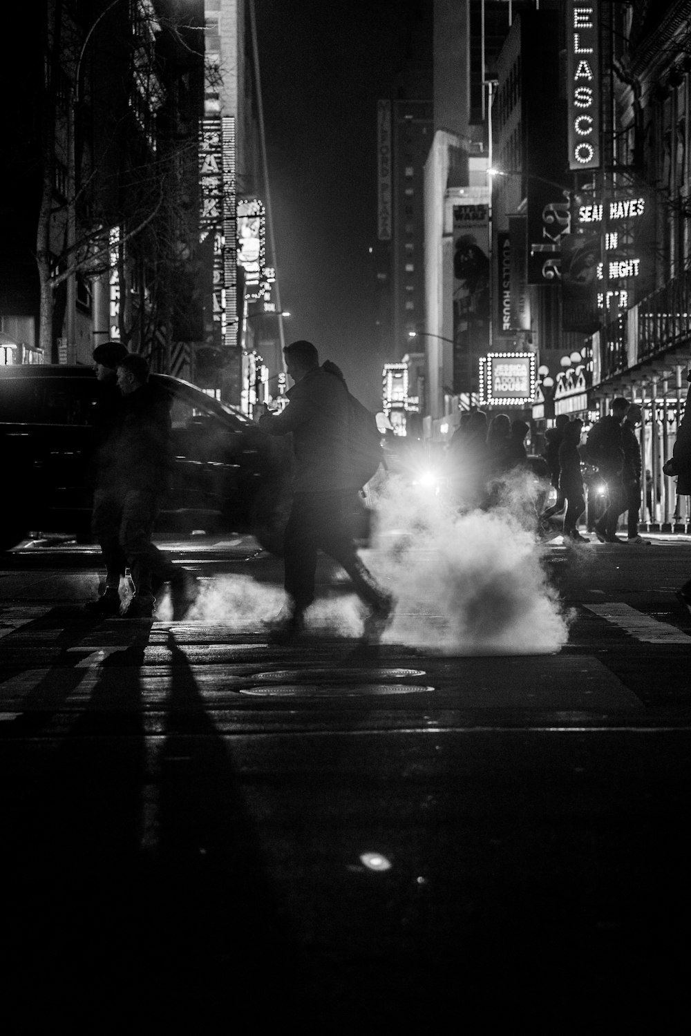 a black and white photo of people crossing the street