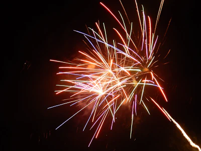 A vibrant display of colorful fireworks bursting in the night sky over a festive crowd