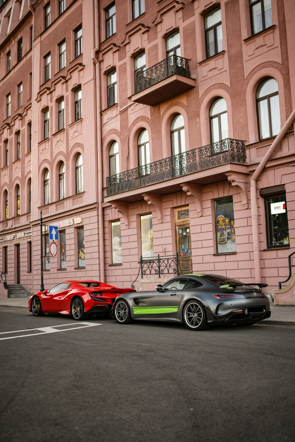 two cars parked in front of a pink building