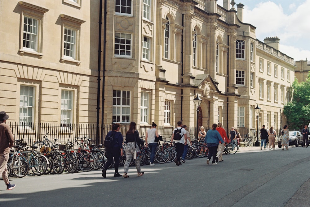 a group of people walking down a street next to tall buildings