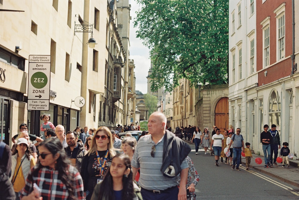 a group of people walking down a street next to tall buildings