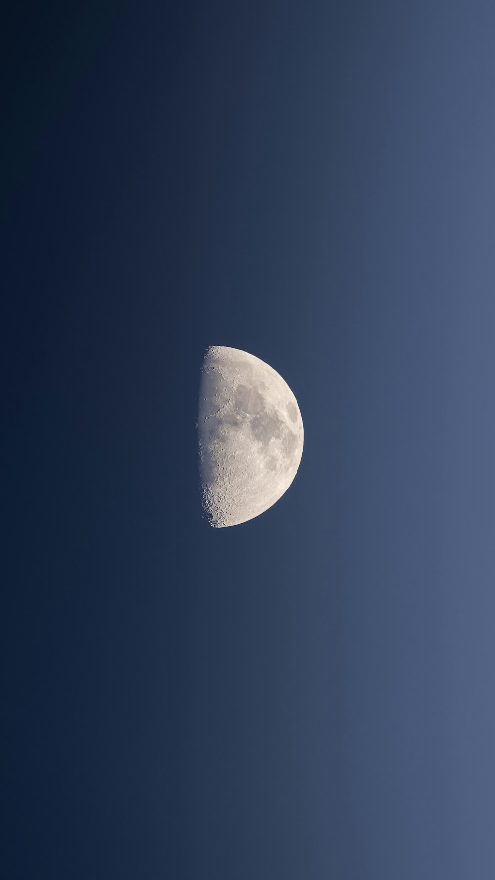 a half moon is seen in a clear blue sky