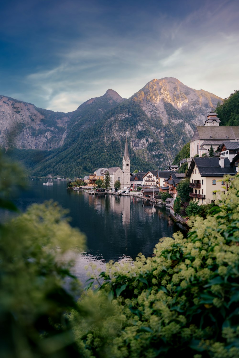 a scenic view of a town on a lake with mountains in the background