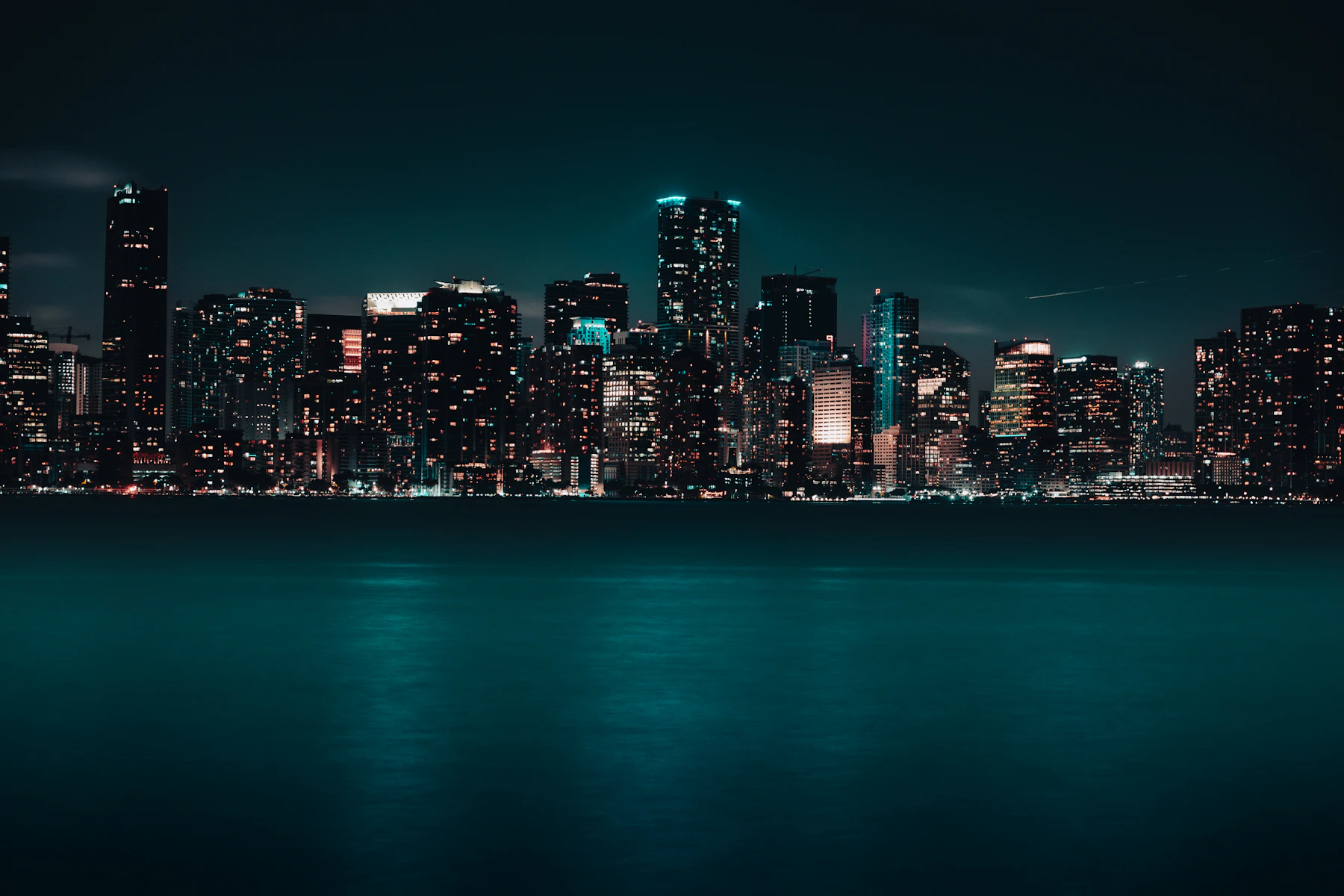 Miami skyline glowing at night over dark calm water
