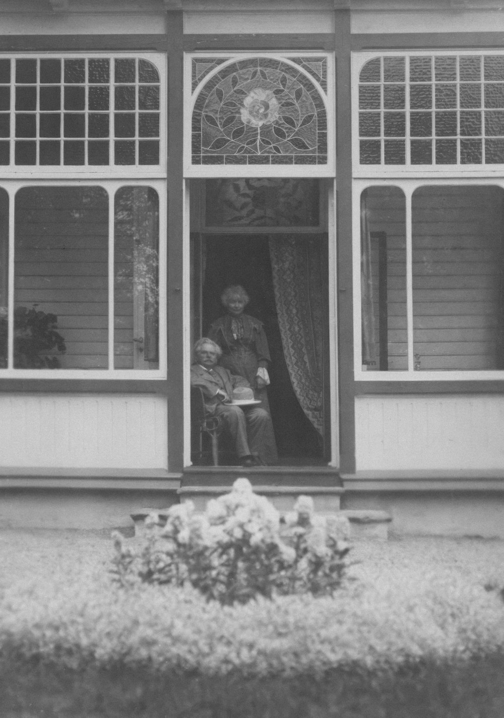 an old black and white photo of two people in a window