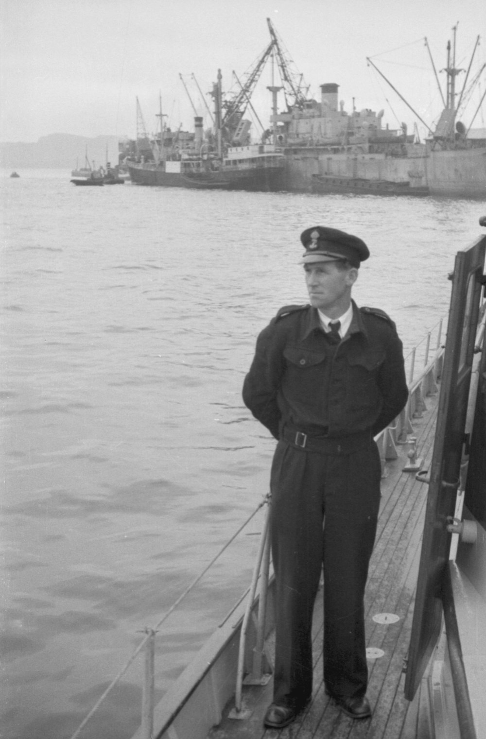 a black and white photo of a man standing on a boat