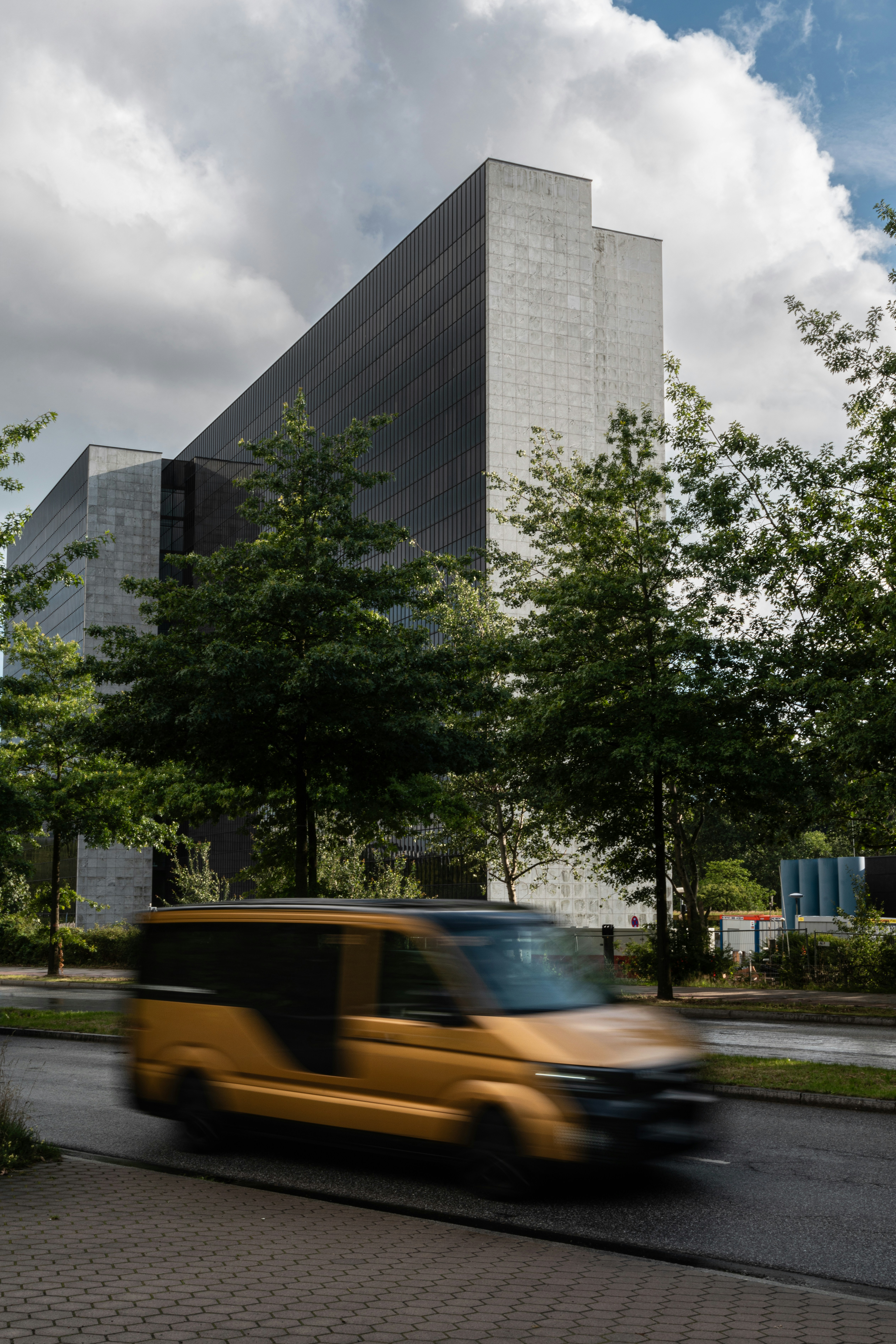 a yellow van driving down a street next to a tall building