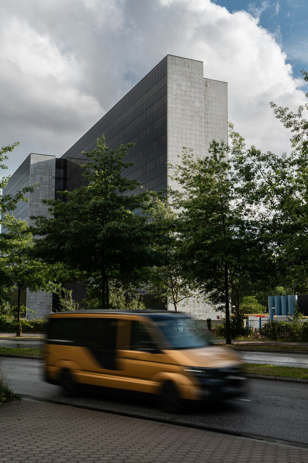 a yellow van driving down a street next to a tall building