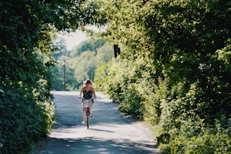 A candid photo of a person riding a bicycle in a sunny park, surrounded by greenery.