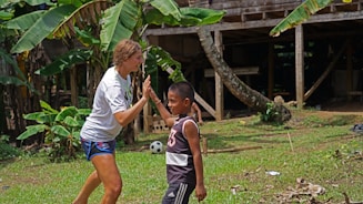 A smiling trainer and client high-fiving outdoors with the sun shining brightly behind them