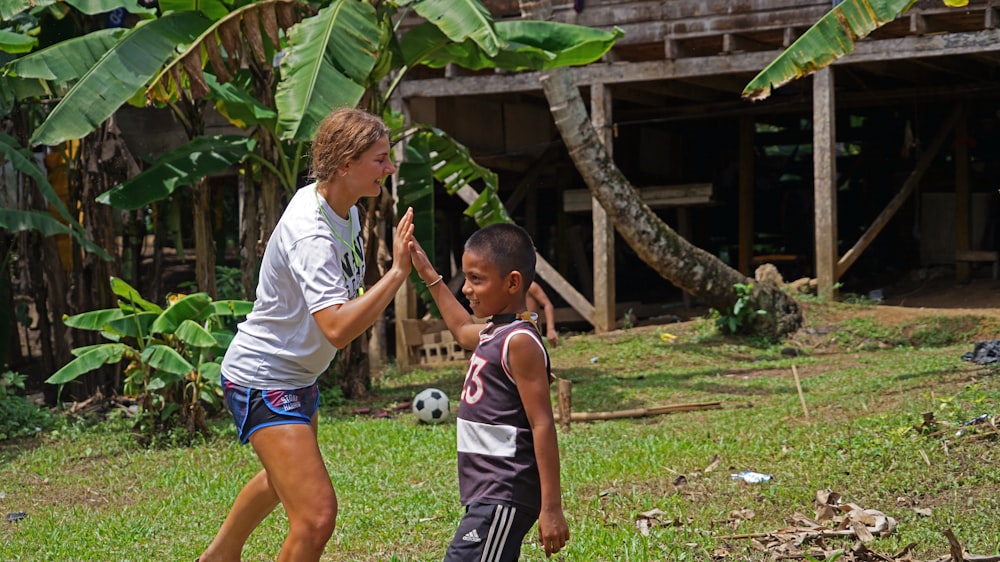 a woman and a boy are playing soccer