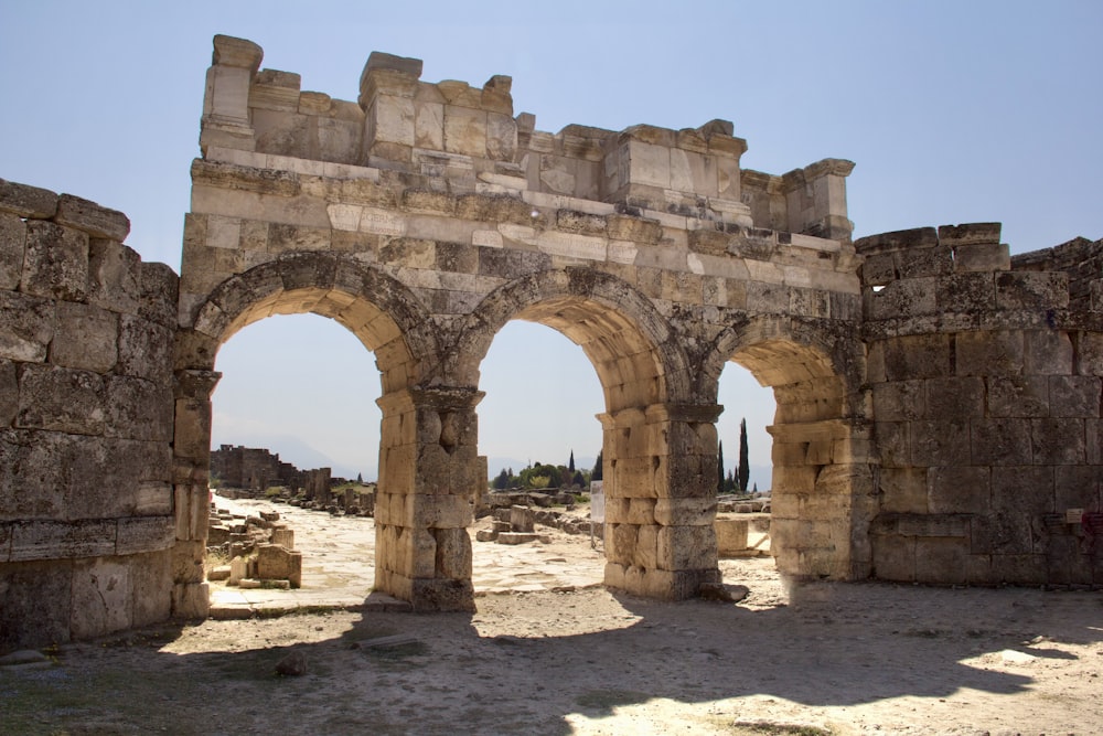 a stone arch in the middle of a dirt field