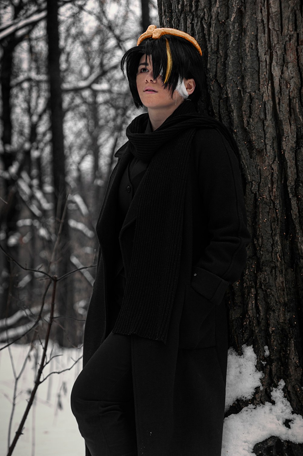 a woman standing next to a tree in the snow