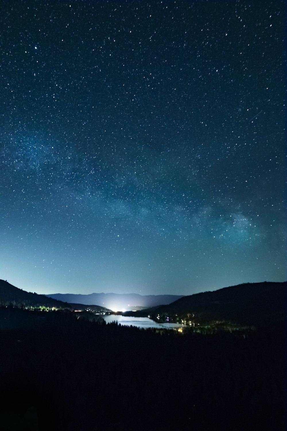 the night sky with stars above a lake