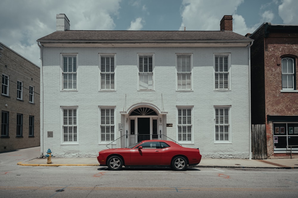 a red car parked in front of a white building