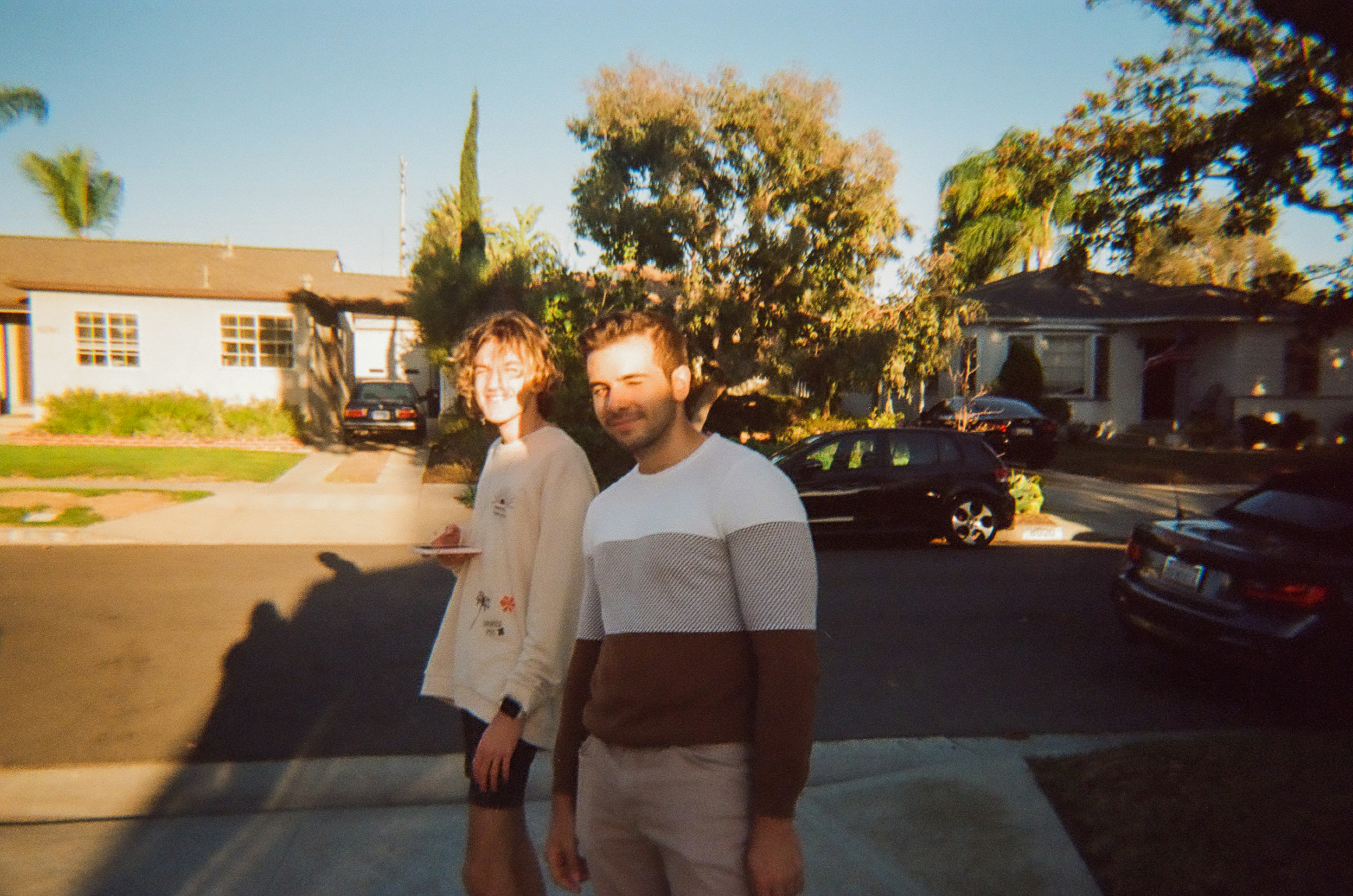 A young couple standing proudly in front of their first suburban home