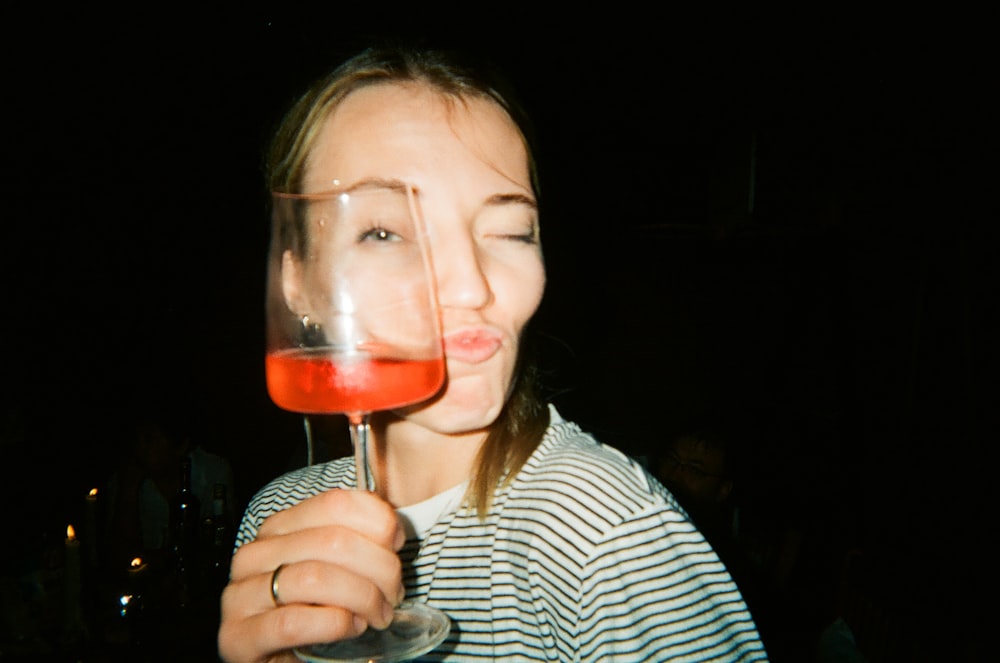 a woman holding a wine glass with a liquid inside of it