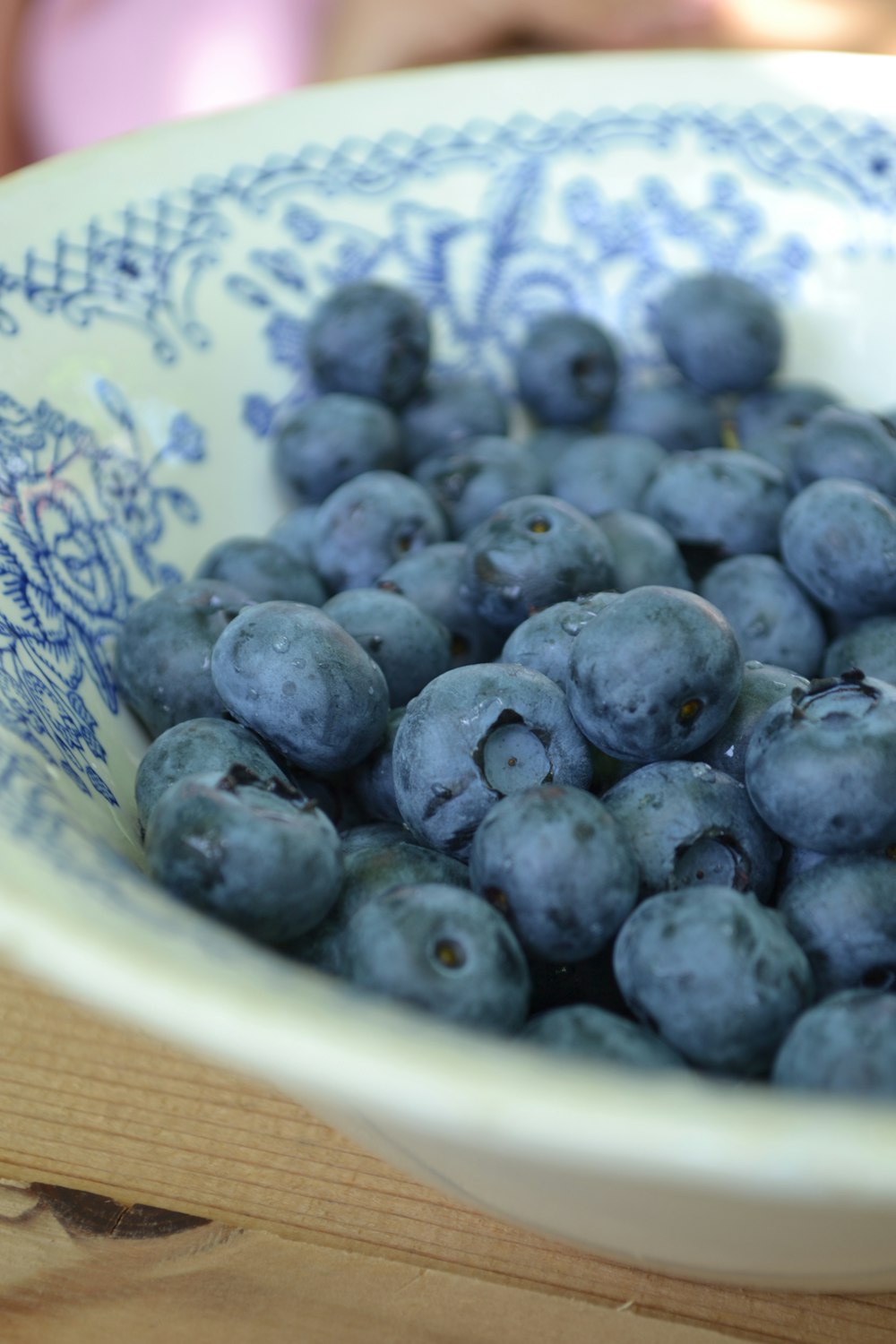 a bowl filled with blueberries sitting on top of a wooden table