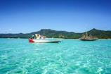 Tourists enjoying a boat excursion on calm turquoise waters under a bright sky.