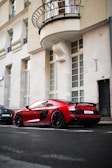 A sleek red sports car parked on a city street at sunset.