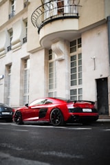 A sleek red sports car parked on a city street at sunset.