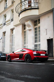 A sleek red sports car parked on a city street at sunset.