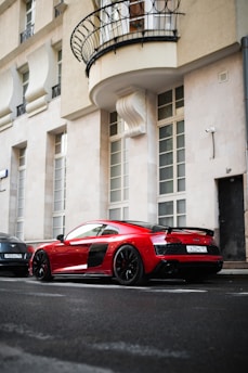 A sleek red sedan parked on a sunlit city street, highlighting its shiny exterior and modern design.
