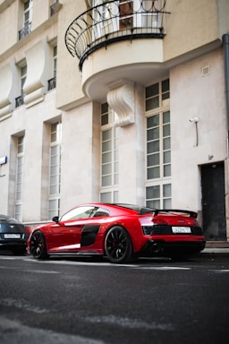 A sleek red sports car parked on a city street at sunset.