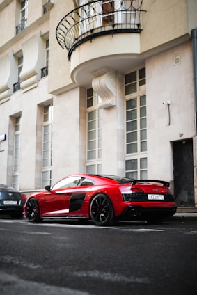 A sleek red sedan parked on a city street in sunlight