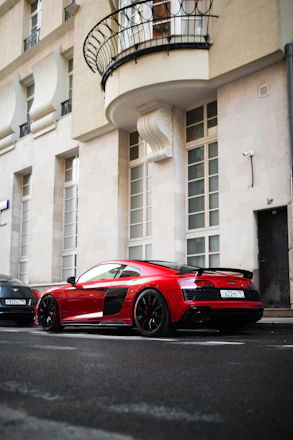 A sleek red sports car parked on a city street at sunset.