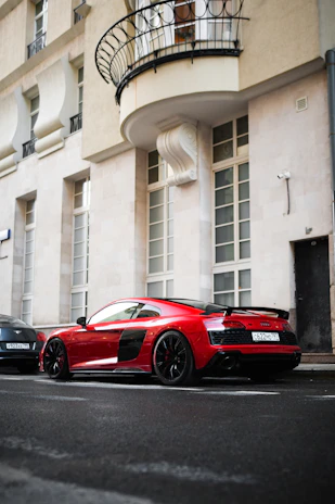 A sleek red sports car parked on a city street at sunset.