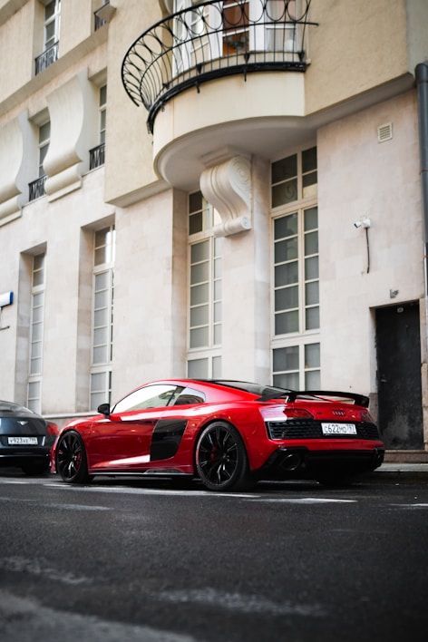 A sleek red sports car parked against a modern city skyline.