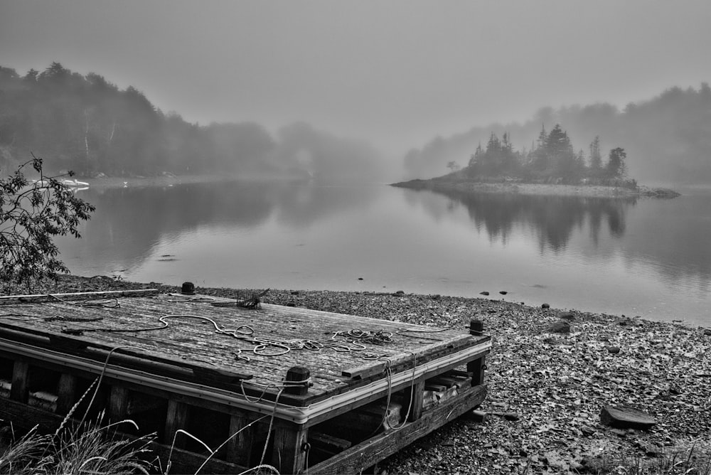 an old boat sitting on the shore of a lake