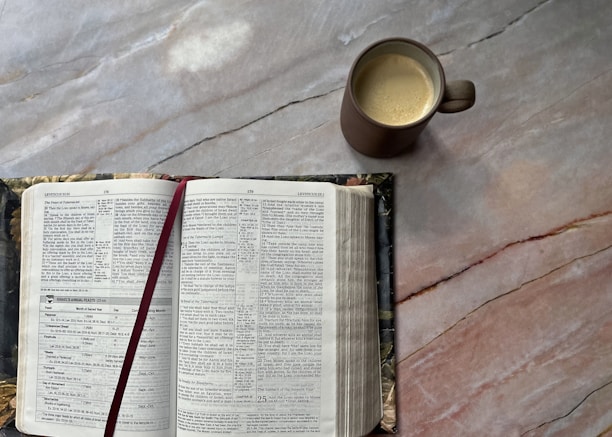 An open ebook on a desk with a cup of coffee and a notepad beside it.